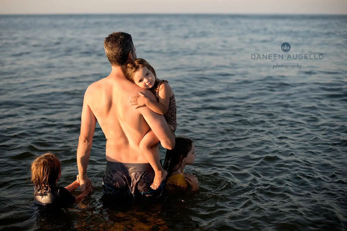 A Man Holding a Girl and a Boy in Water