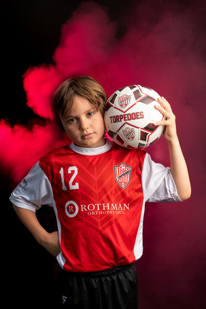 A young boy holding a soccer ball in his hands.