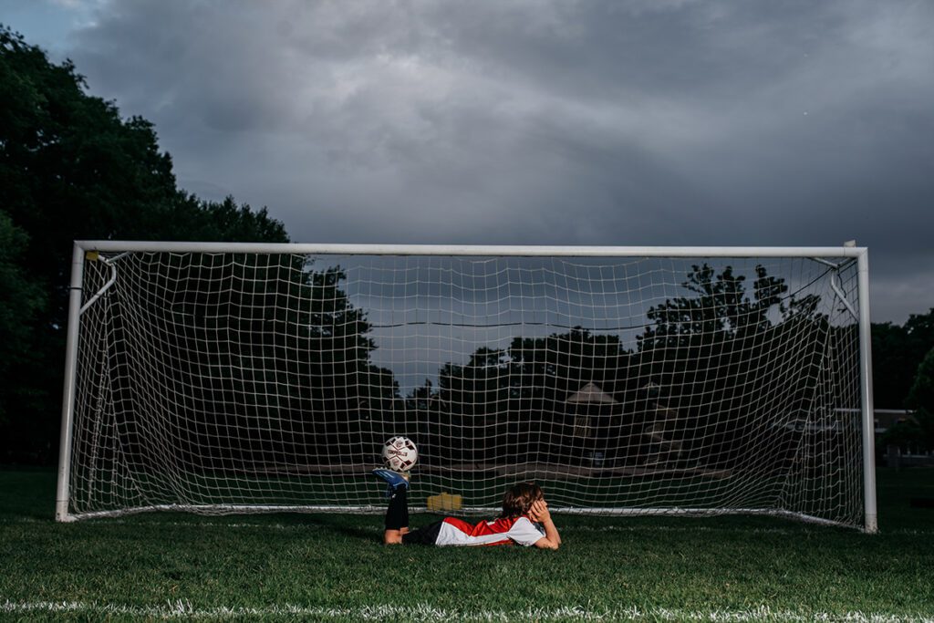 A person laying in the grass with a baseball glove.