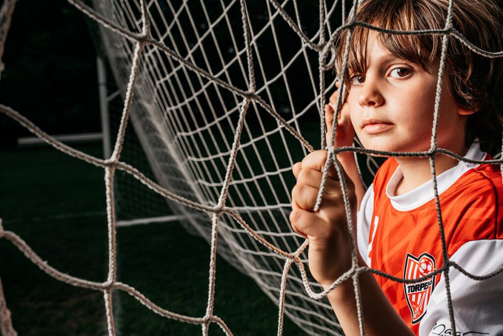 A young boy is looking through the net.